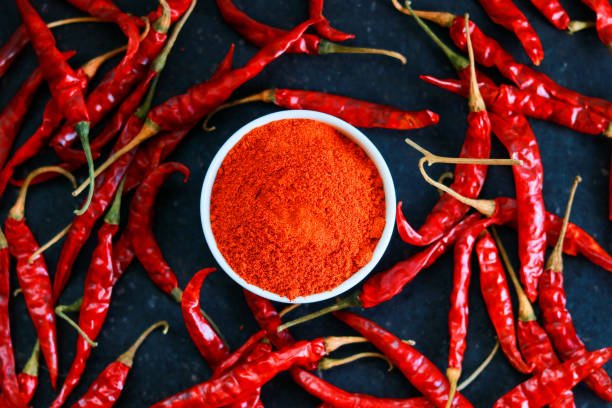 Red hot chili pepper powder in a white bowl on a dark background